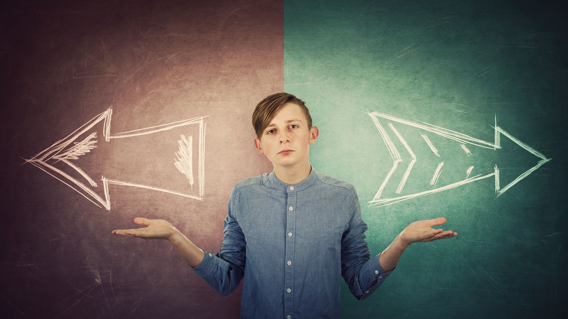 Perplexed teenage boy spread outstretched arms, balancing hands gesture, two options to choose right or left, decision concept. Split blackboard and arrows going in two different ways.