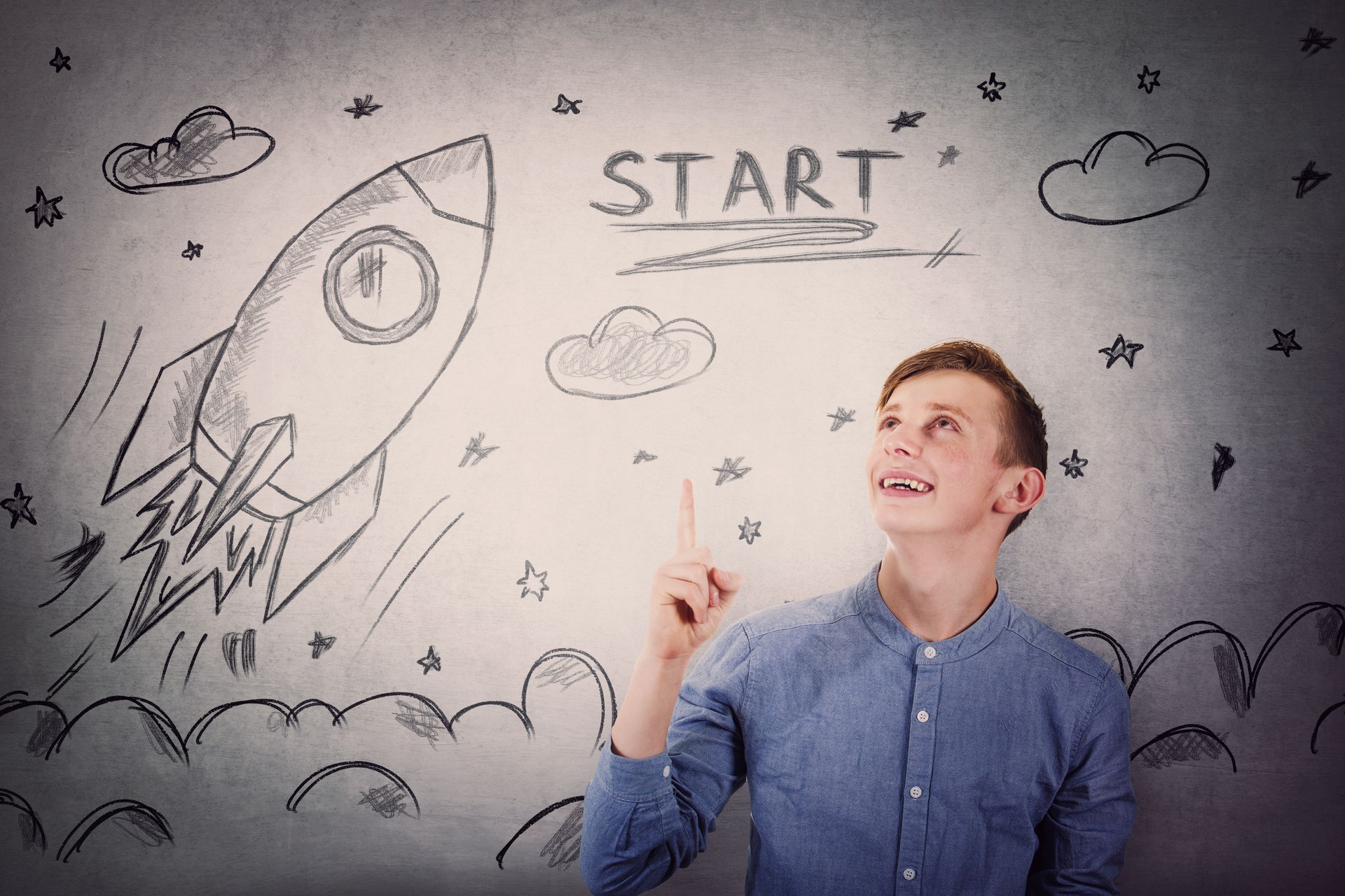 Joyful student guy pointing finger and looking up, happy face expression, showing rocket ship startup sketch, taking off in space.